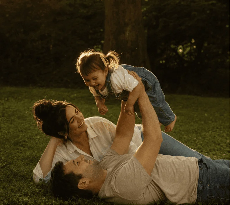 Enhanced version of the same photo, upscaled and sharpened so the toddler's face, the grass, and the denim texture all read clearly